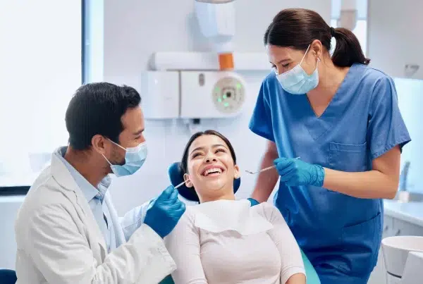 Dentists examining smiling patient in orthodontics appointment.