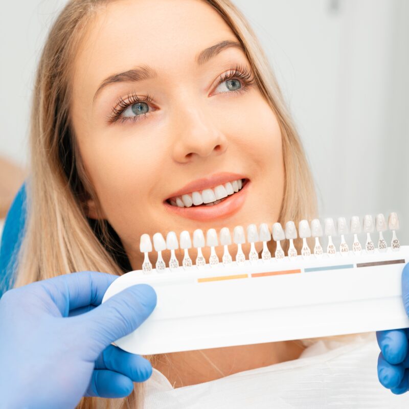 Woman getting teeth color-matched at dentist.